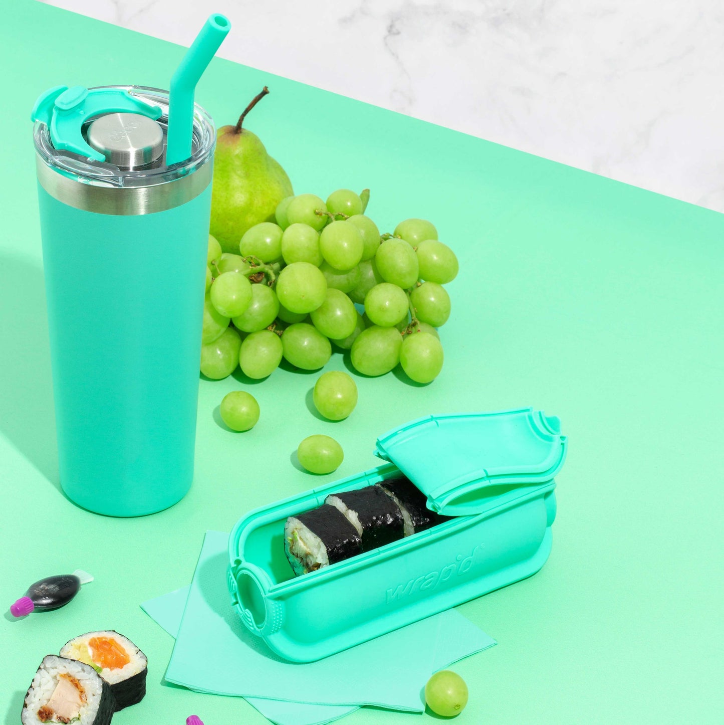 Aqua Wrap'd Open Showing Sushi Inside with Grapes and a Matching Aqua Drink Bottle Next To It