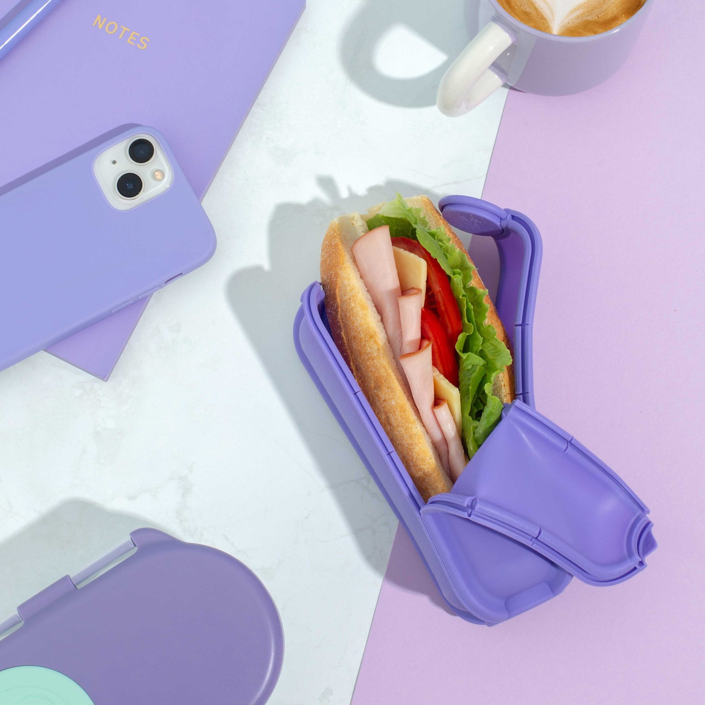 Purple Wrap'd Open Showing Fresh Ham and Salad Roll Inside with Purple Phone And Notebook Next To It